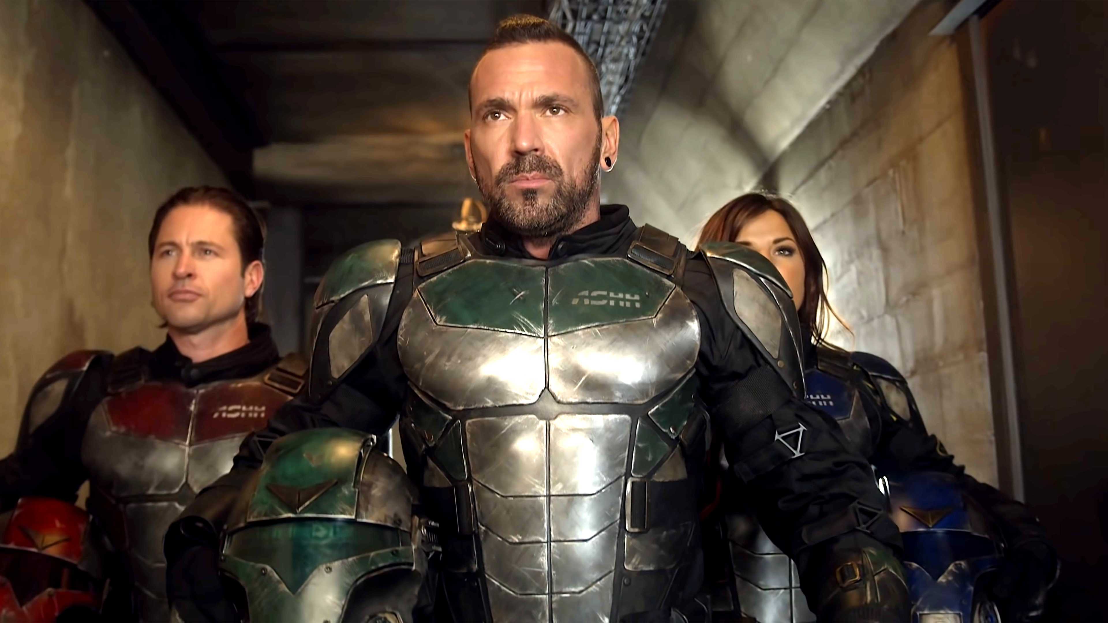 Jason David Frank como Eric caminando por un pasillo con dos personas detrás de él, todos con trajes de superhéroe, en Legend of the White Dragon.