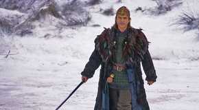 Sam Neill with a sword in the snow in the 1998 fantasy film Merlin.