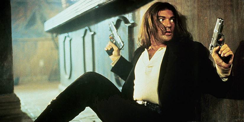 Antonio Banderas as El Mariachi hiding behind a bar while holding two pistols in Desperado