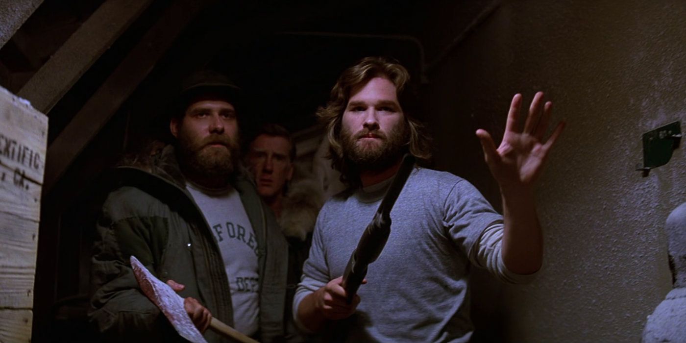 Kurt Russell as MacReady raising his hand up with other men behind him in The Thing