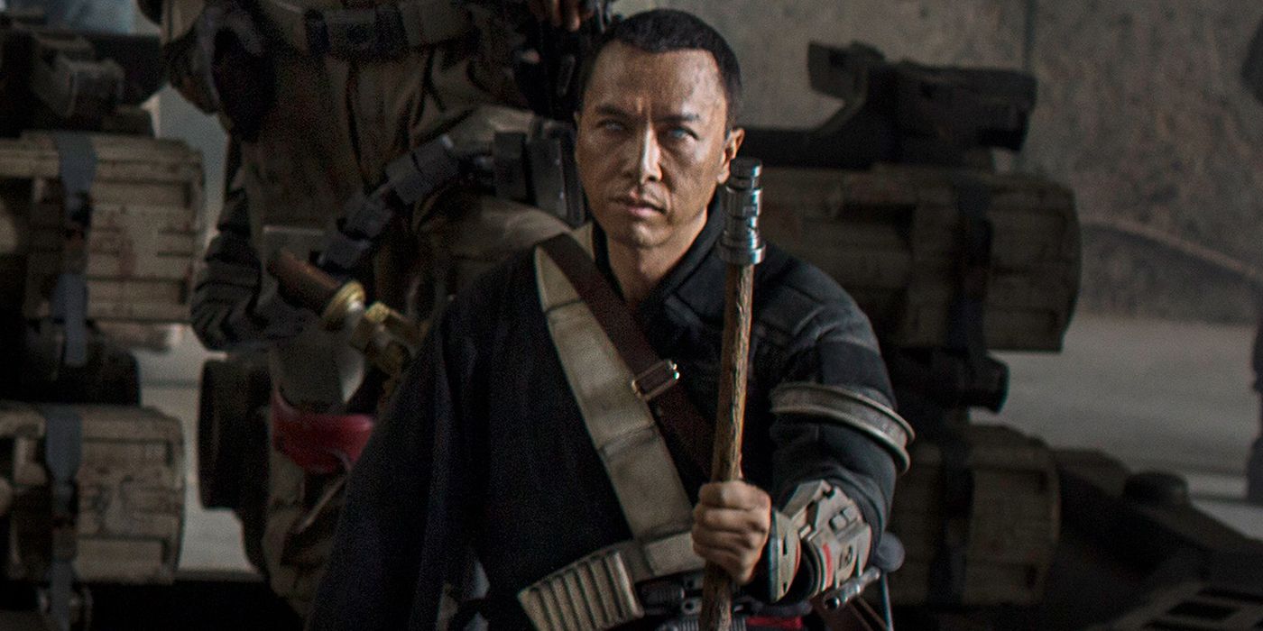 Chirrut Îmwe holds his staff while listening to his team's plan in Rogue One: A Star Wars Story