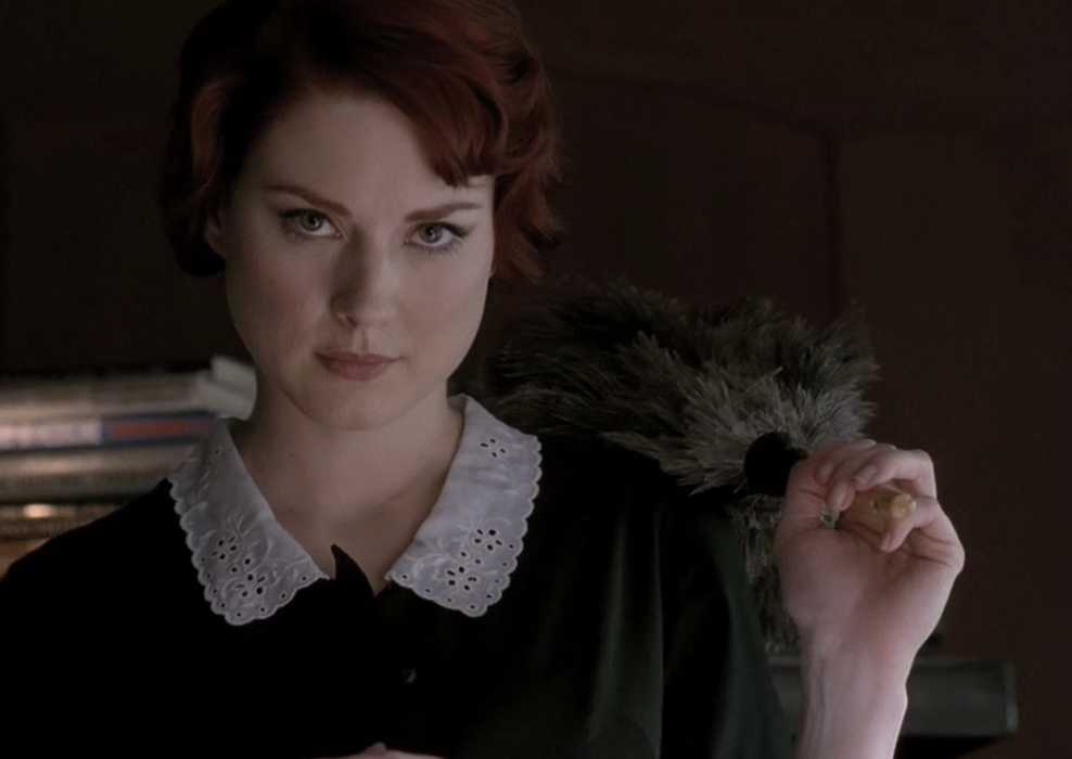 Alexandra Breckenridge as Young Moira holding a feather duster in American Horror Story