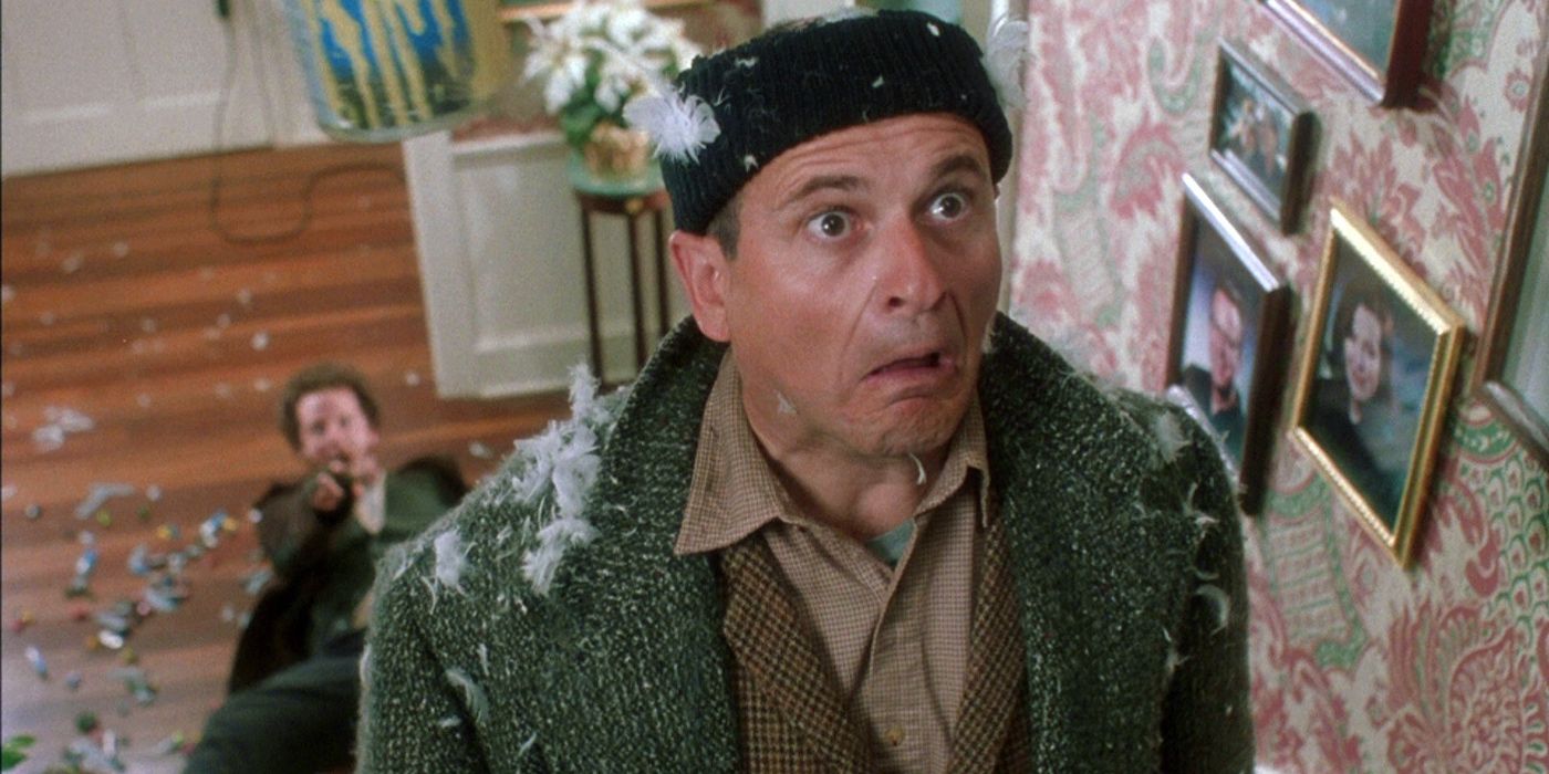 Joe Pesci as Harry lightly covered in feathers in while walking up the stairs with Daniel Stern as Marv laying on the ground behind him in Home Alone