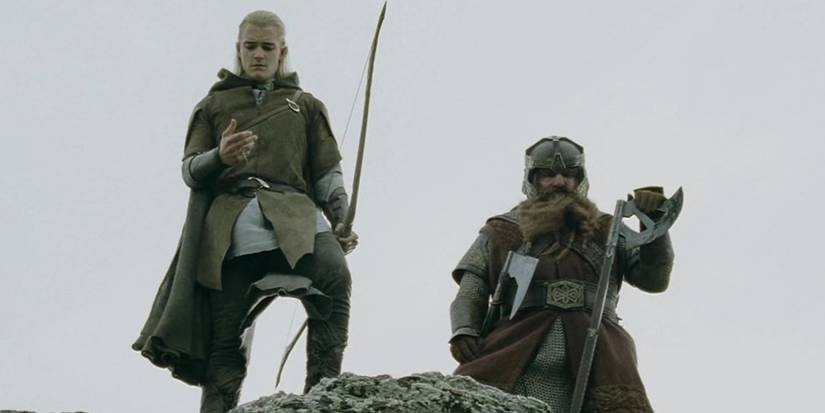 Gimli and Legolas standing together at the top of a rocky outcrop in The Lord of the Rings. 