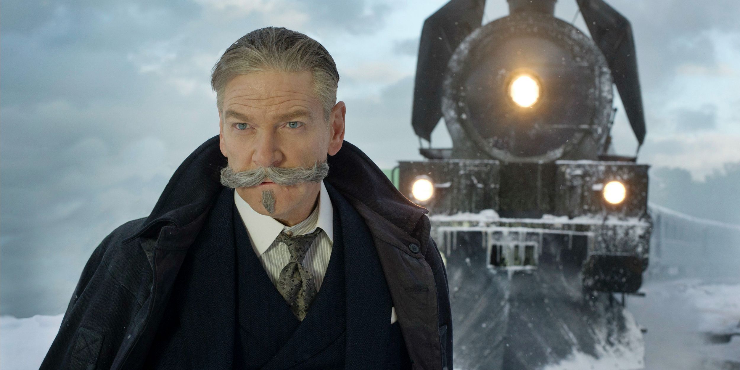 Kenneth Branagh as Hercule Poirot standing in front of the Orient Express for Murder on the Orient Express