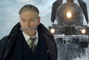 Kenneth Branagh as Hercule Poirot standing in front of the Orient Express for Murder on the Orient Express