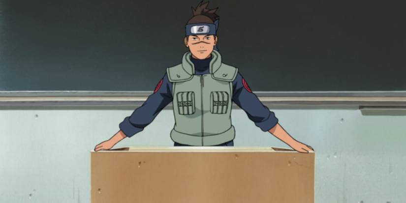Iruka smiling a little bit and standing at his desk in Naruto.