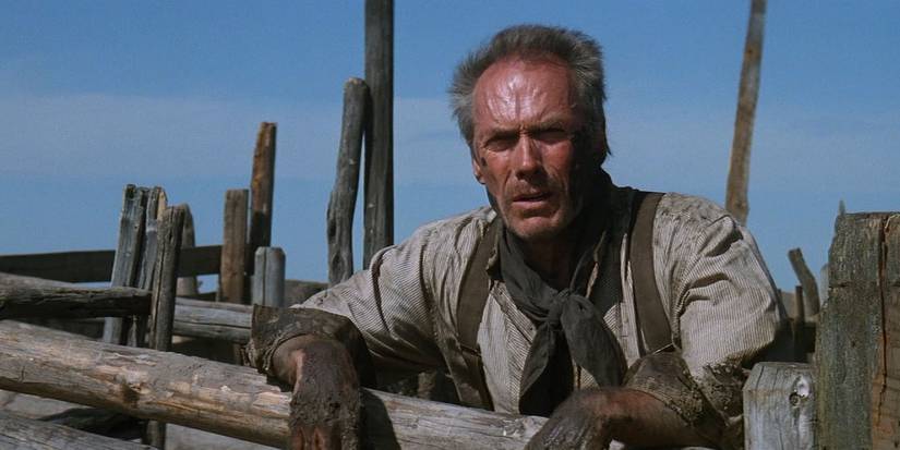 Clint Eastwood as William Munny standing by a fence in Unforgiven 1992