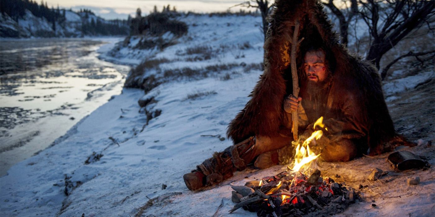 Hugh Glass (Leonardo DiCaprio) sits by a campfire in The Revenant