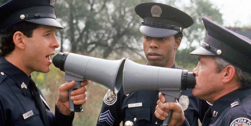 Steve Guttenberg yelling into a megaphone alongside Michael Winslow and G. W. Bailey in Police Academy