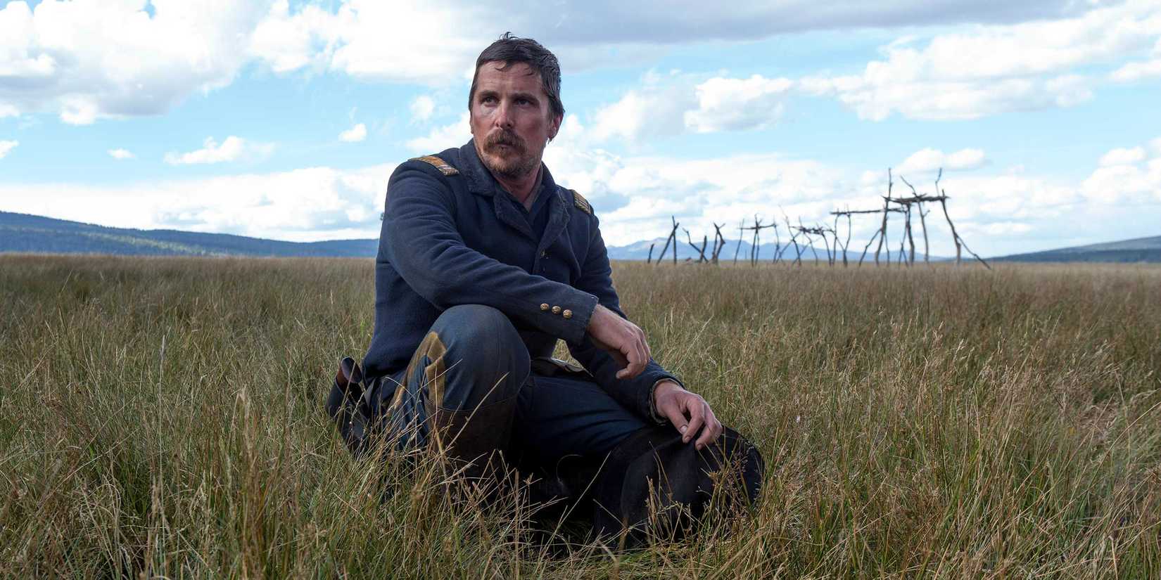 Christian Bale in Hostiles Featured Image sitting in a field