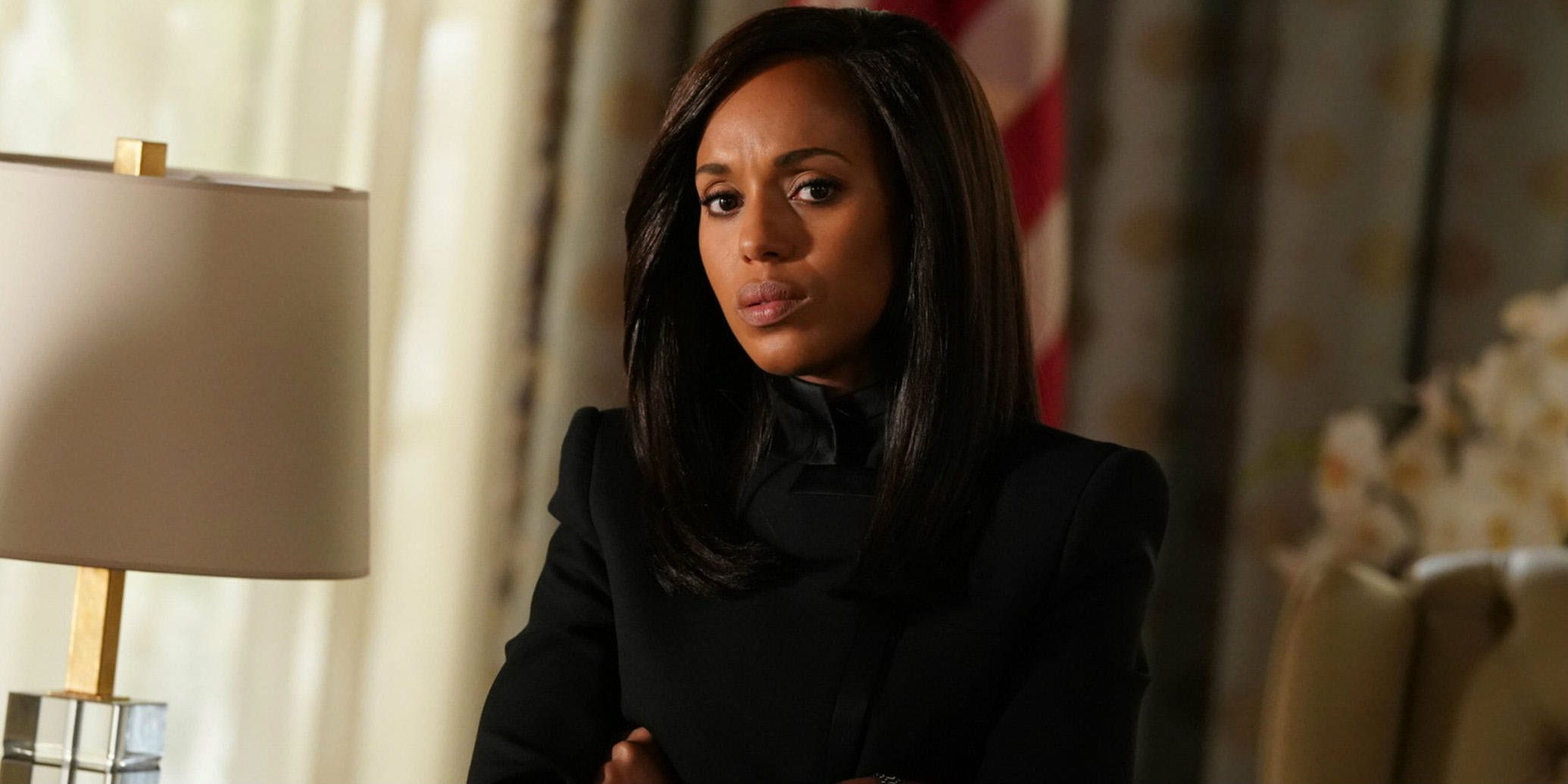 Olivia Pope (Kerry Washington) sitting in her office in front of an American flag in Scandal