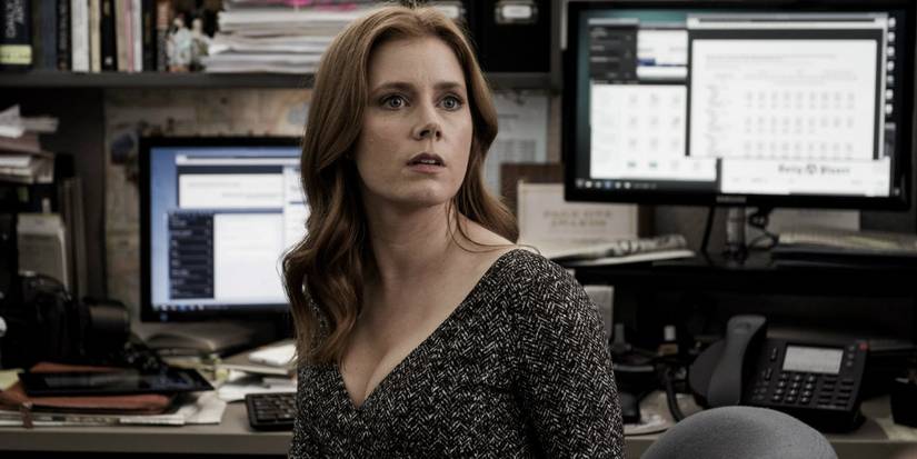 Amy Adams as Louise Banks sitting at desk looking off camera in Arrival.