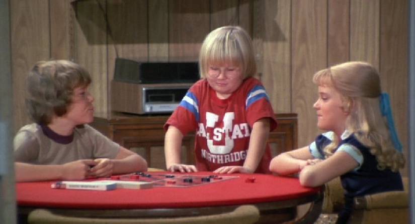 Cousin Oliver stands at a table in The Brady Bunch