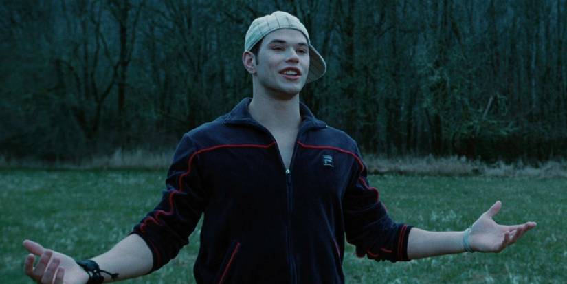 Emmett Cullen (Kellan Lutz) with his hat on sideways and his arms extended in a field in the baseball scene in the Twilight movie