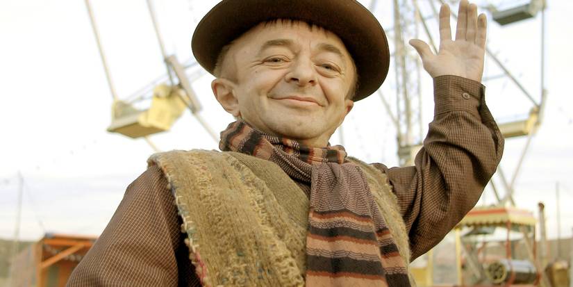 Michael J Anderson von Carnivale, winkt und lächelt.