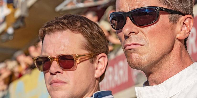 Matt Damon and Christian Bale looking out at the racetrack in Ford v Ferrari