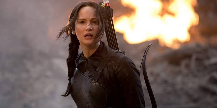Katniss stands in the street in front of a fire in The Hunger Games Mockingjay Part 1.