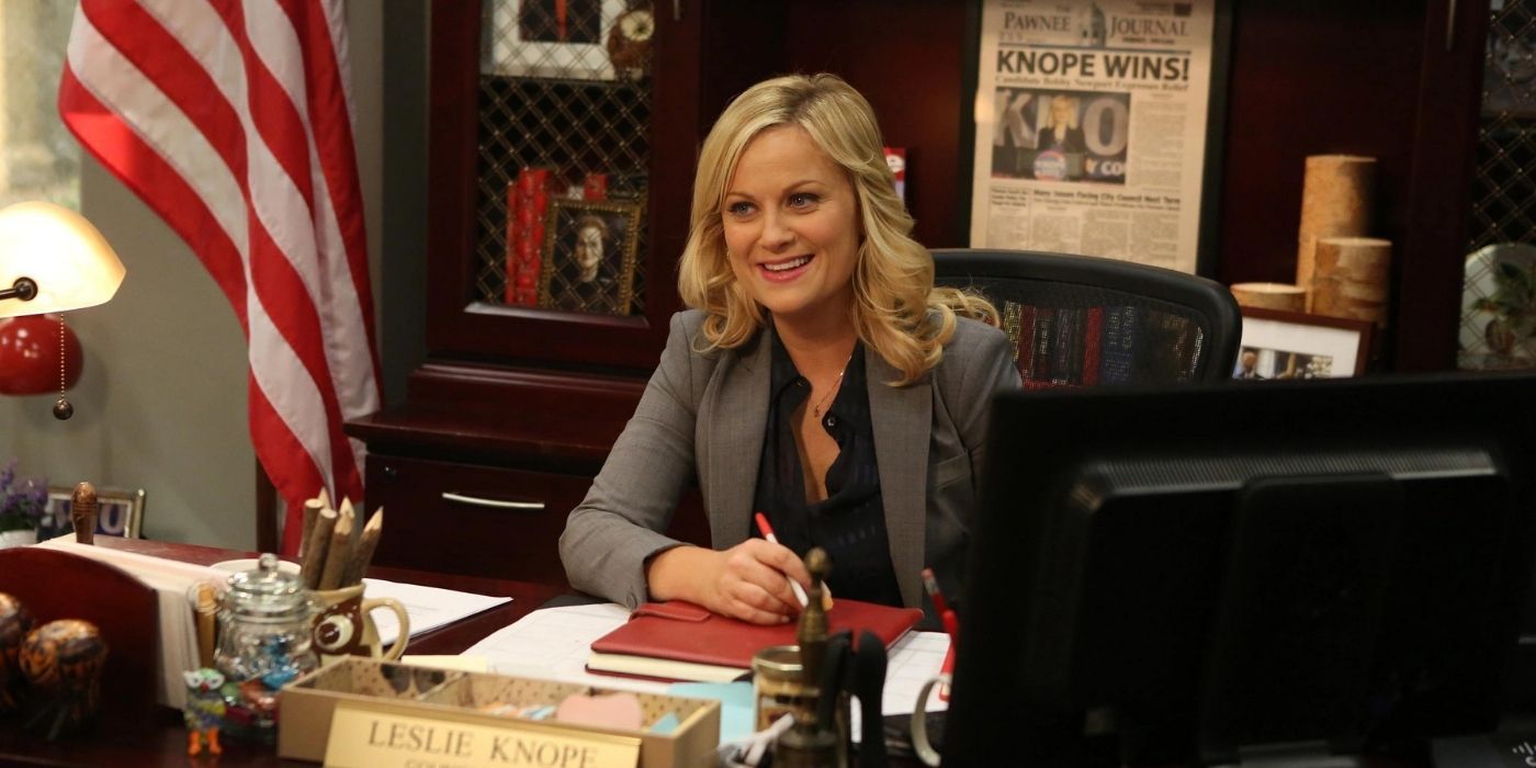 Leslie sitting at her desk in her office smiling on Parks and Rec