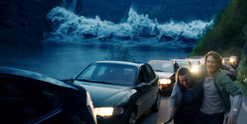 Kristoffer Joner como Kristian Eikjord ajudando Silje Breivik como Anna a se afastar do tsunami na onda