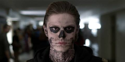 Evan Peters as Tate Langdon in American Horror Story with his face looking like a skull as he walks down the hallway