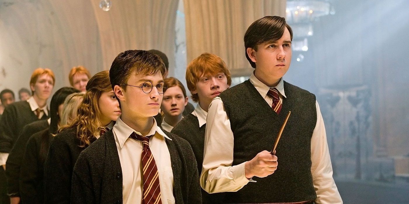 Neville pronto com sua varinha ao lado de Harry Potter com outros alunos atrás dele