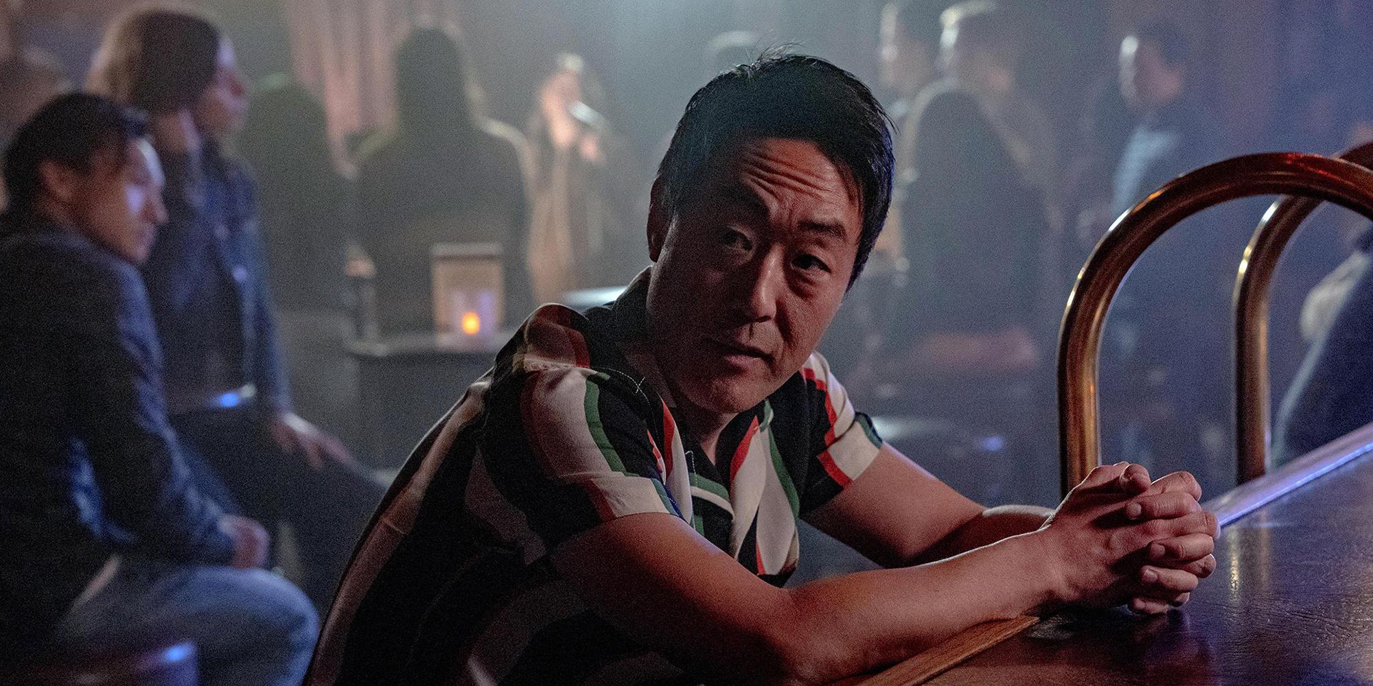 Chimney (Kenneth Choi) sitting at a bar and looking at someone in 9-1-1.