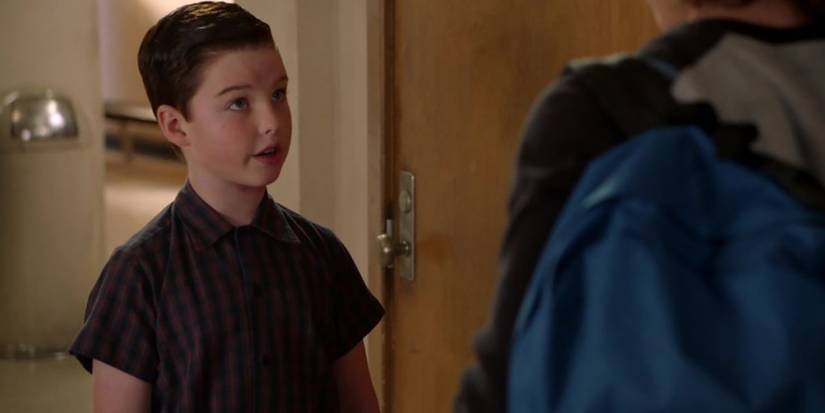 Sheldon looking up at someone talking in a scene from Young Sheldon.