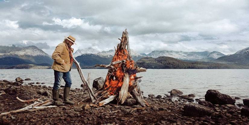 Francis Mallmann stoking a large wood fire on a lake shore in Chef's Table.
