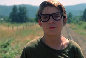 Teddy (Corey Feldman) looking slightly scared in an open field in Stand by Me
