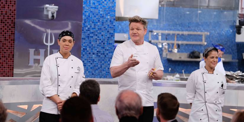 Gordon Ramsay standing in the kitchen with two contestants from Hell's Kitchen.