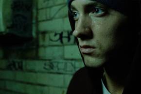 Eminem sitting by a wall with graffiti in 8 Mile.