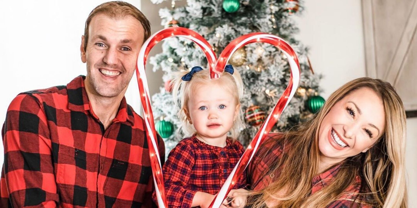 MAFS Jamie Otis Doug Hehner in buffalo plaid pajamas with child smiling in front of the christmas tree