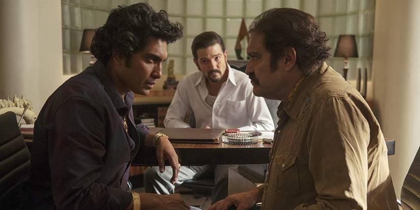 Felix (Diego Luna) watching two men stare at one another in Narcos: Mexico.