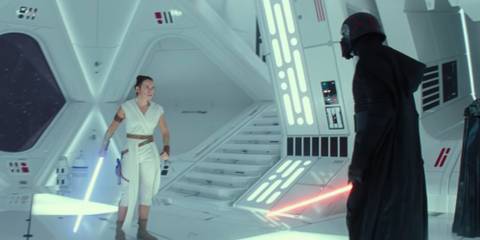 Daisy Ridley as Rey stands holding her blue lightsaber opposite Kylo Ren holding his red lightsaber in The Rise of Skywalker