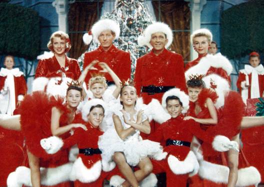 The cast of the musical within White Christmas posing as they sing in red and white outfits