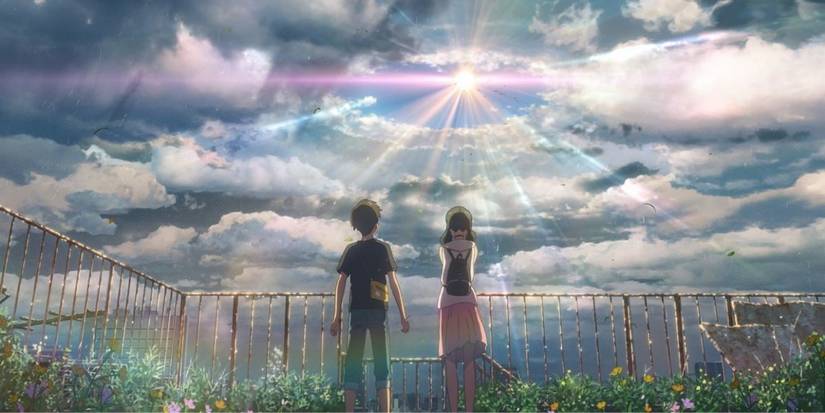 Weathering With You's two characters looking up at a clearing in the sky with the sun bursting through.
