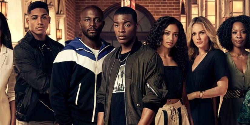 The cast of All American posing in front of the high school.