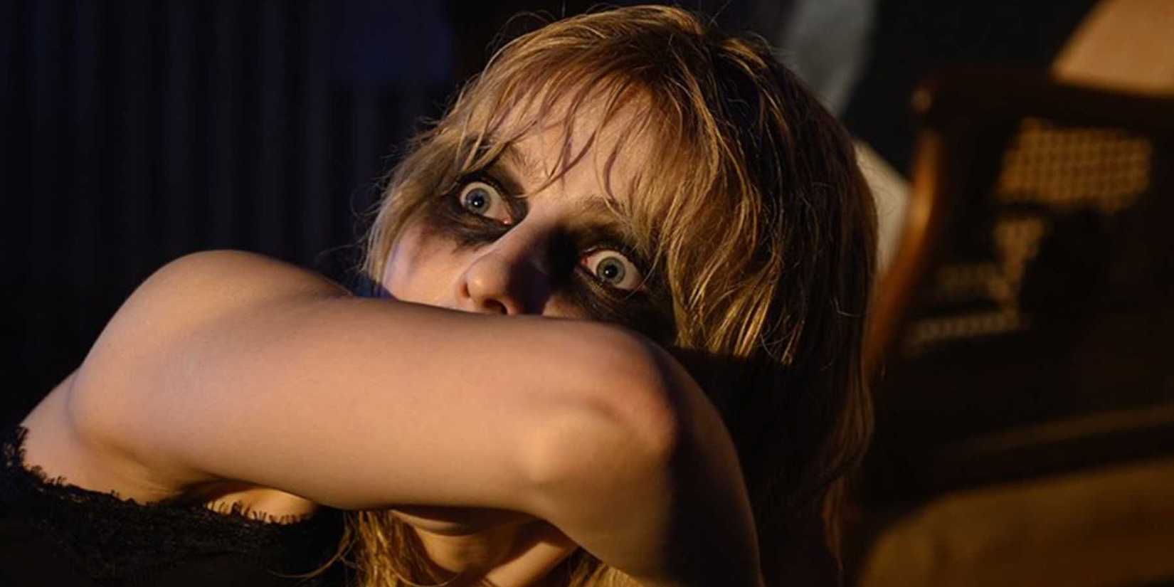 Thomasin McKenzie as Ellie looking scared with her arm over her mouth in Last Night in Soho