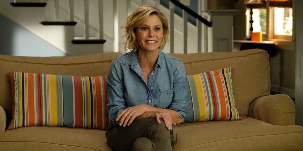 Julie Bowen as Claire in Modern Family sitting on the couch and smiling