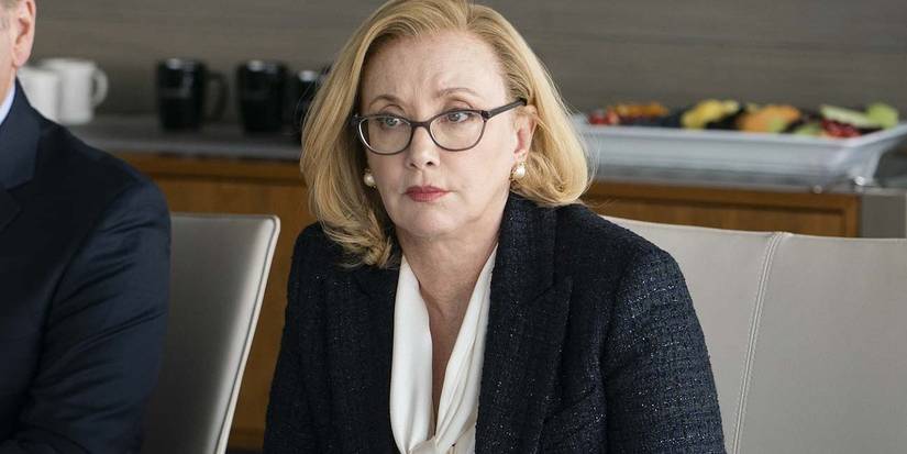 Gerri Kellman wearing glasses and looking across a table in Succession