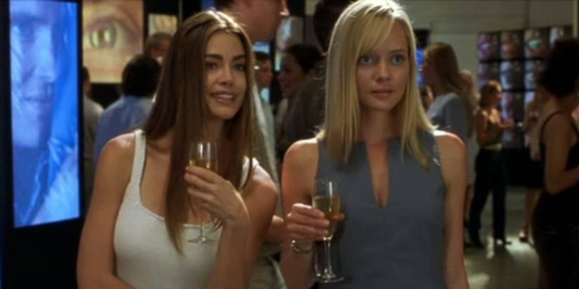 Denise Richards e Marley Shelton em O Ataque segurando taças e olhando para fora da tela