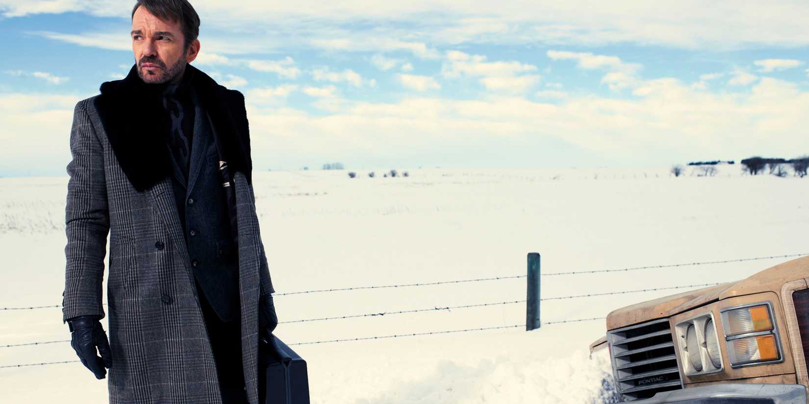 Billy Bob Thornton as Malvo, holding a brief case by the side of a snowy road in Fargo