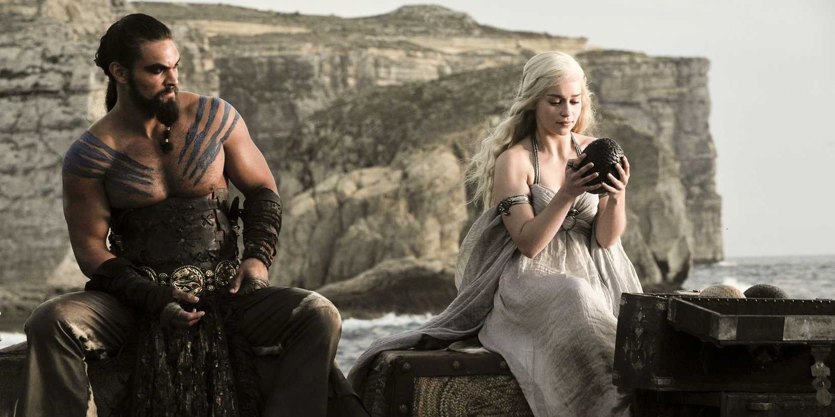 Khal Drogo with Daenerys Targaryen sitting together as she looks at a dragon egg in Game of Thrones