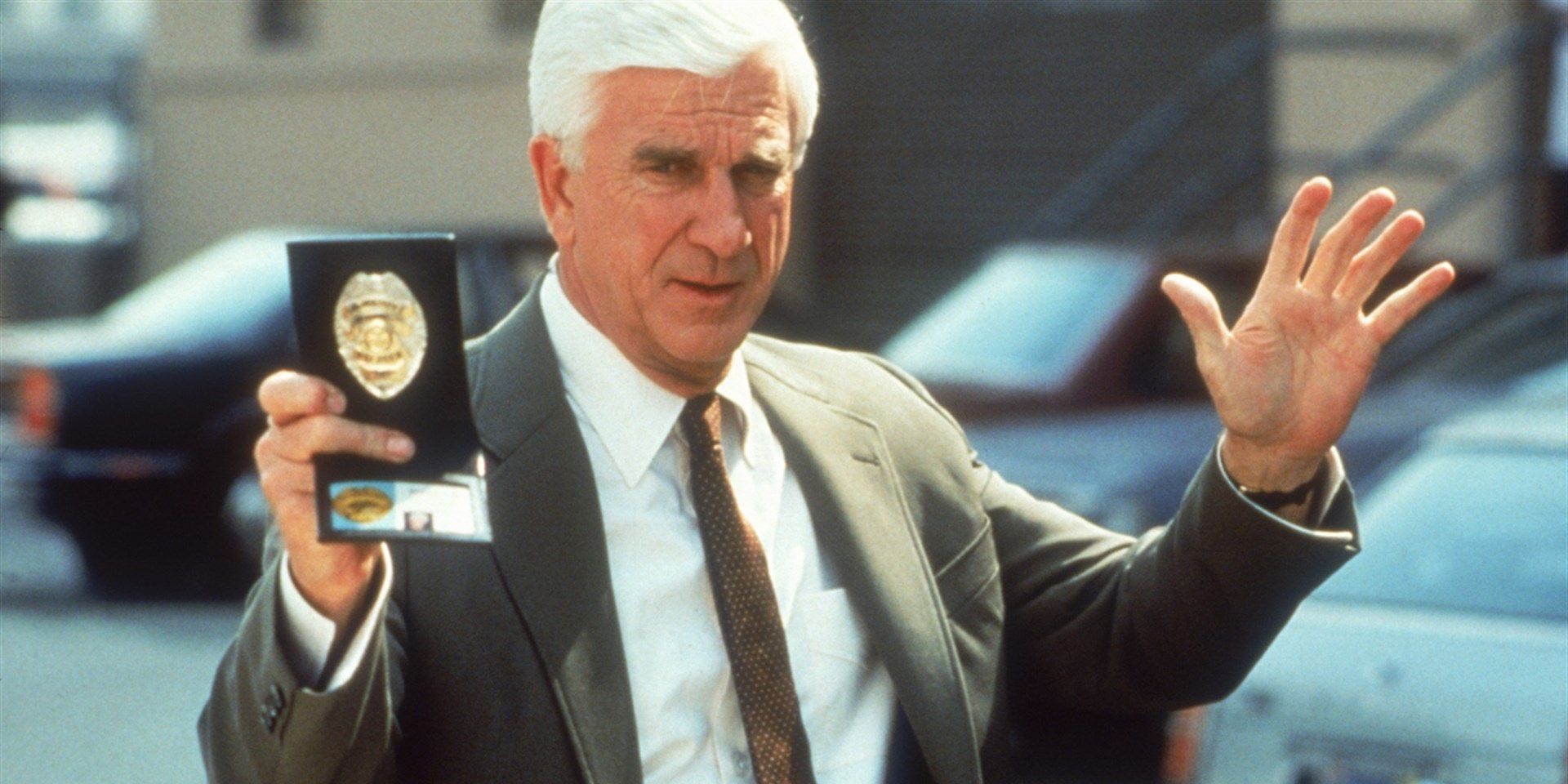 Leslie Nielsen as Frank holds up his badge in The Naked Gun