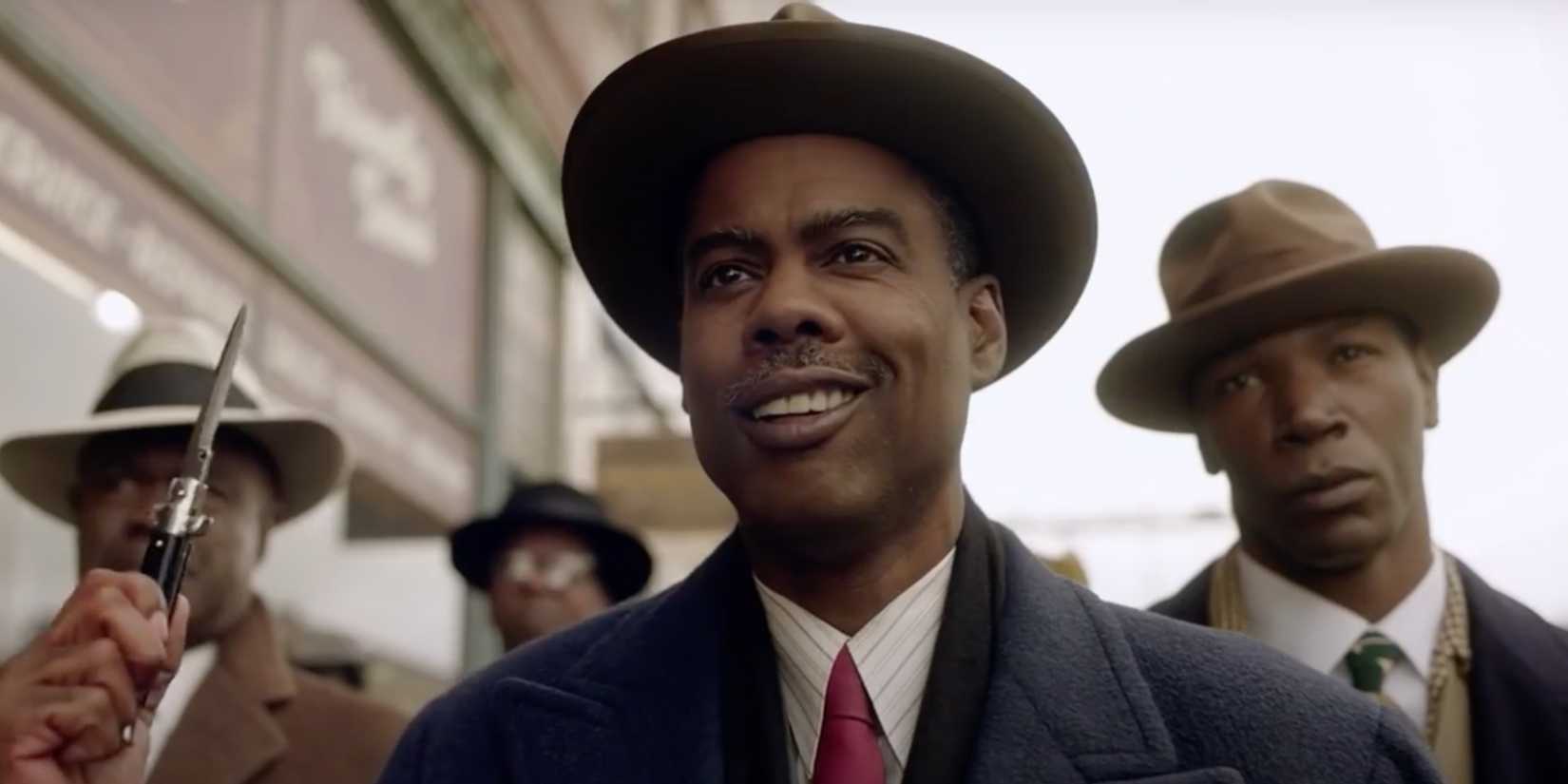 Loy Cannon (Chris Rock) sorrindo e segurando uma faca com seus homens atrás dele na 4ª temporada de Fargo