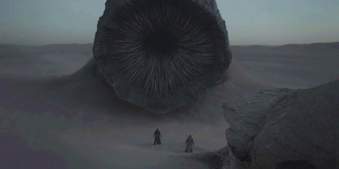Two people looking at a giant sandworm in the desert in Dune (2021)