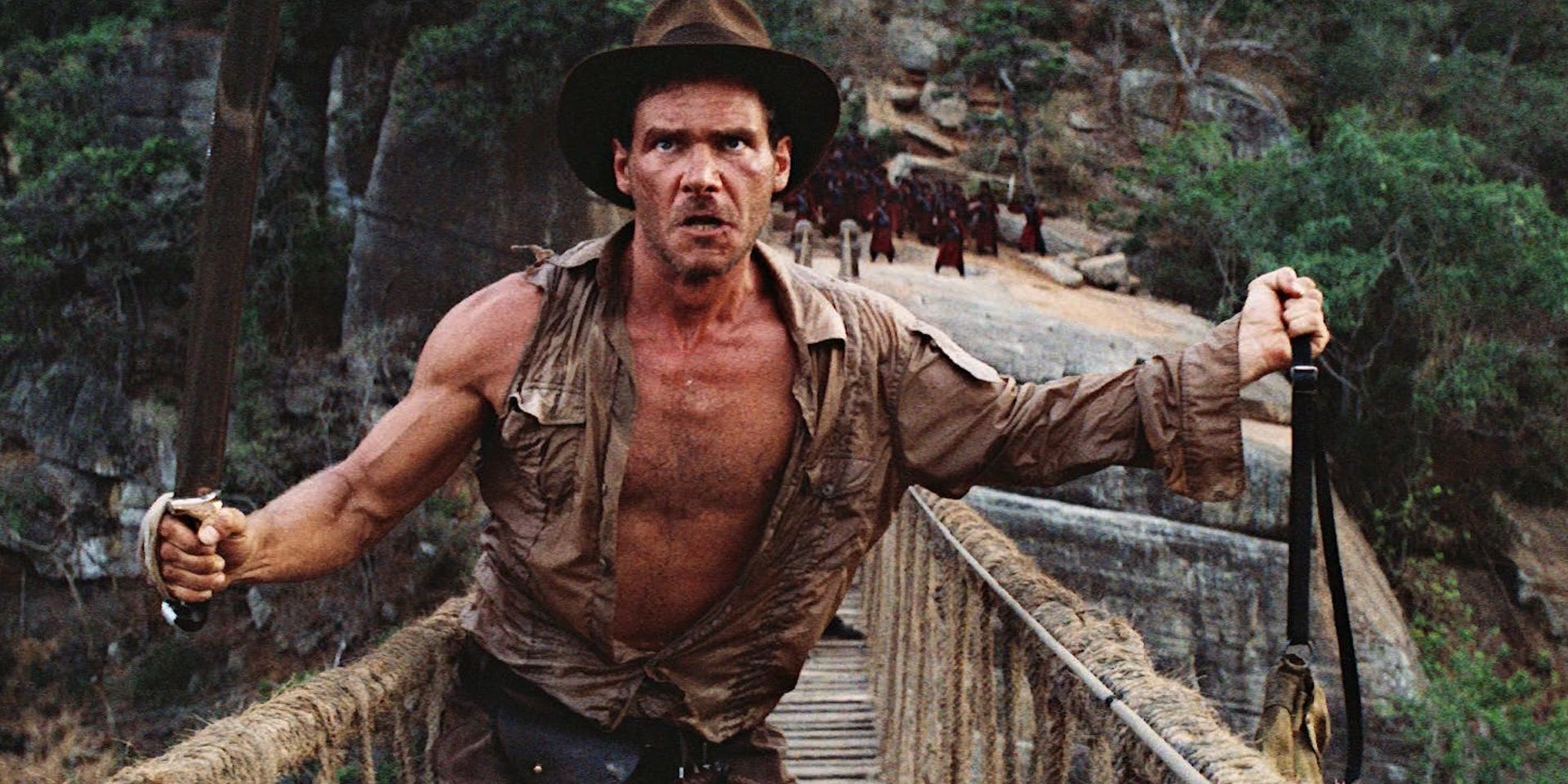 Indiana Jones holds a bag and a sword in Indiana Jones and the Temple of Doom.