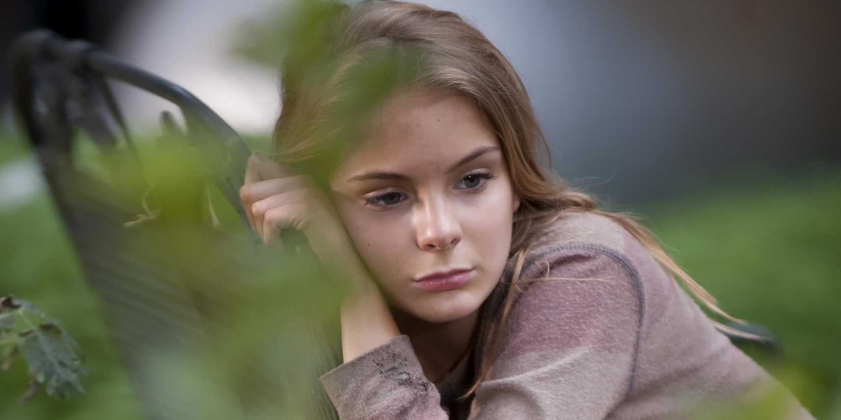 Lizzie (Brighton Sharbino) from The Walking Dead leaning against a chair