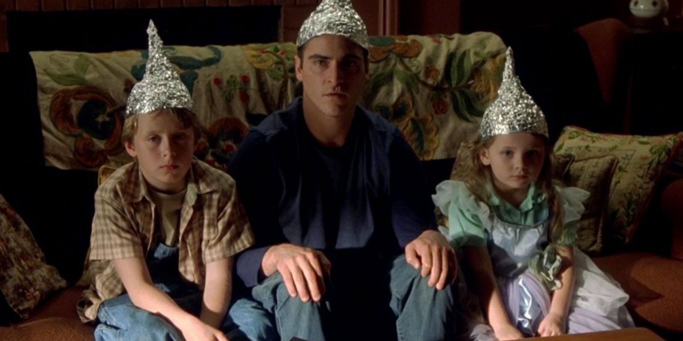 Merrill (Joaquin Pheonix), Beau (Abigail Breslin), and Morgan (Rory Culkin) sitting with tinfoil caps on their heads in Signs.